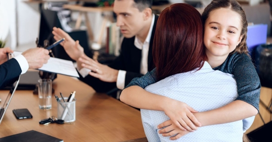child hugging mom while dad argues with lawyer