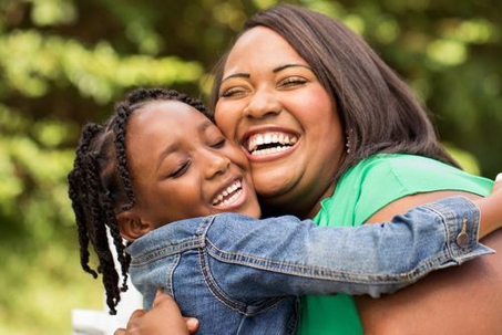 Mother and daughter smiling and hugging each other tightly.