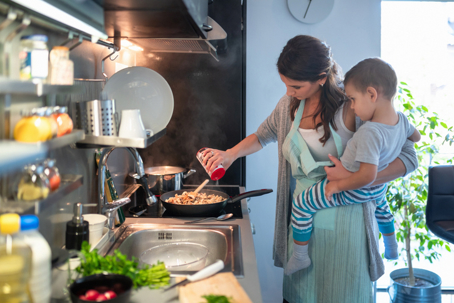 mother cooking while carrying her child