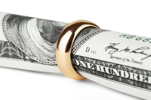 a roll of hundred-dollar bills inside of a wedding ring symbolizing alimony