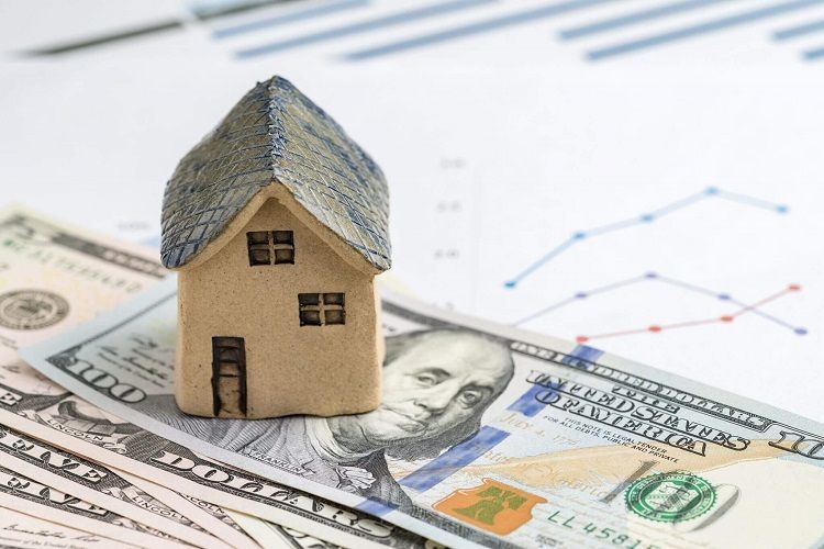 a figure of a house sitting on top of a stack of cash symbolizing an inheritance